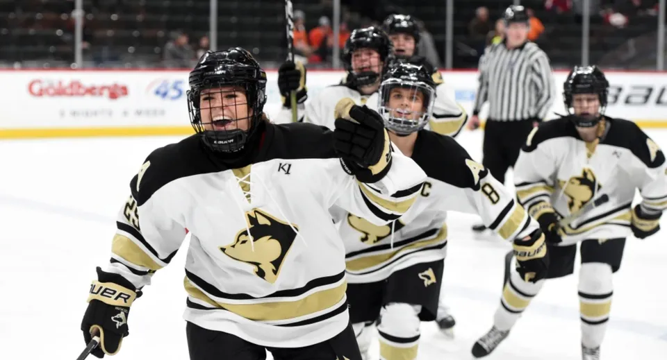 Un gruppo di giocatori di hockey con maglie bianche e nere gioca sul ghiaccio presso il Daniel McIntyre Collegiate Institute.