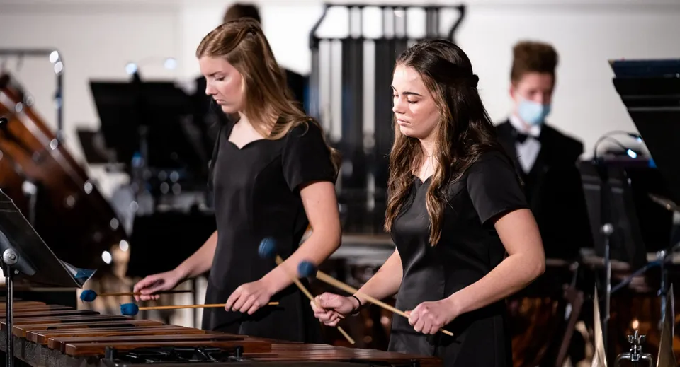 Due studentesse della Stillwater Christian School suonano strumenti a percussione sul palco.