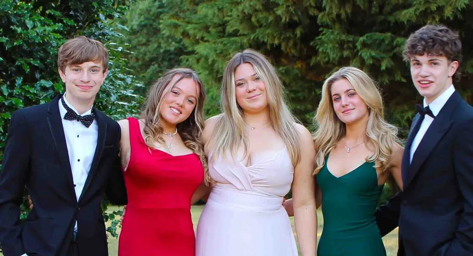 Un gruppo di cinque giovani in abito formale posa nel bosco all'interno della proprietà del Stoke College.