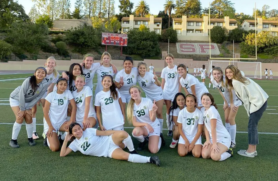 Un gruppo di giocatrici di calcio della Santa Barbara High School posa insieme sul campo da calcio.