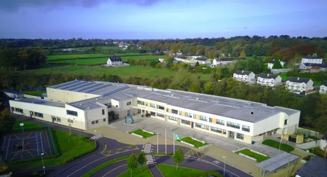 L'edificio moderno a più piani della Gallen Community School è circondato da un paesaggio rurale con colline e boschi.