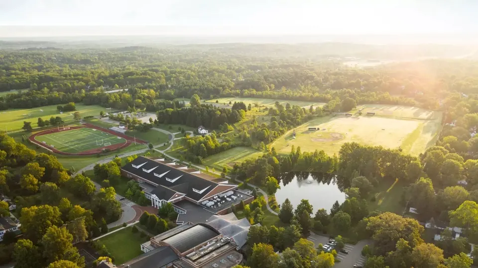 La Western Reserve Academy mostra un impianto sportivo con edifici scolastici e un lago immerso in un'area boschiva.