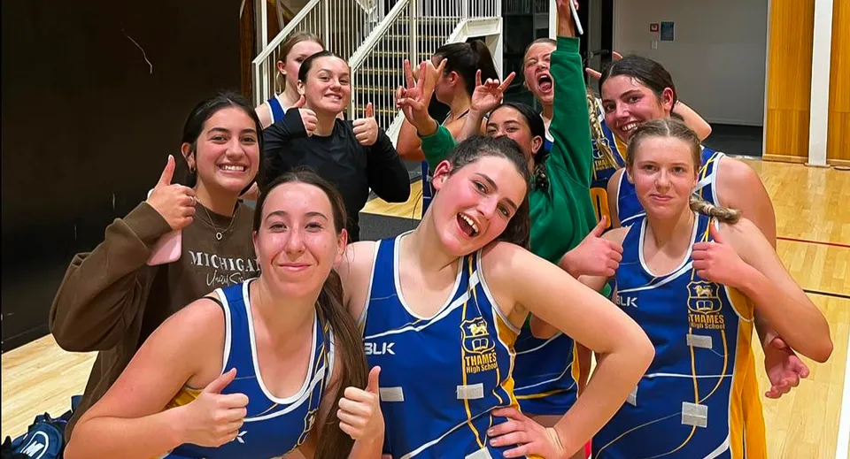 Un gruppo di studenti della Thames High School posa in divise sportive blu all'interno di una palestra.