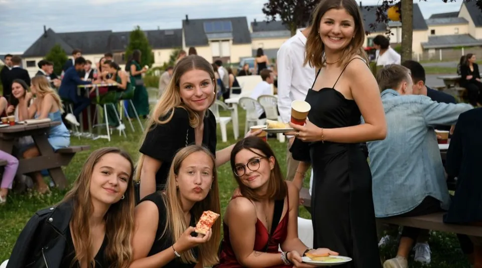 Un gruppo di giovani donne in abito formale posa insieme nel giardino del campus del Lycée Immaculée Jean Paul II.