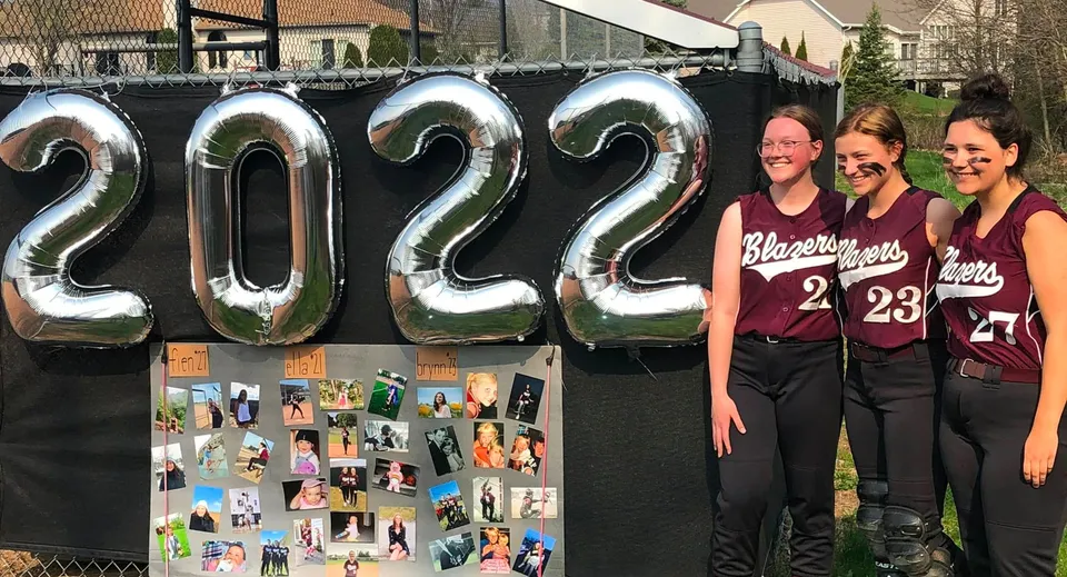 Tre studentesse in piedi davanti a grandi numeri gonfiabili con l'anno 2022 alla N.E.W. Lutheran High School.