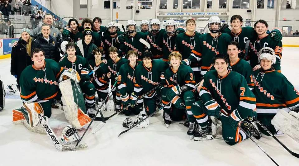 Un gruppo di giocatori di hockey posa insieme sulla pista di ghiaccio nel campus del Hopkinton Public School District.