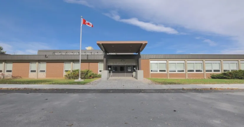 L'edificio moderno a più piani della North Dundas District High School con la bandiera canadese sul tetto sotto un cielo blu.