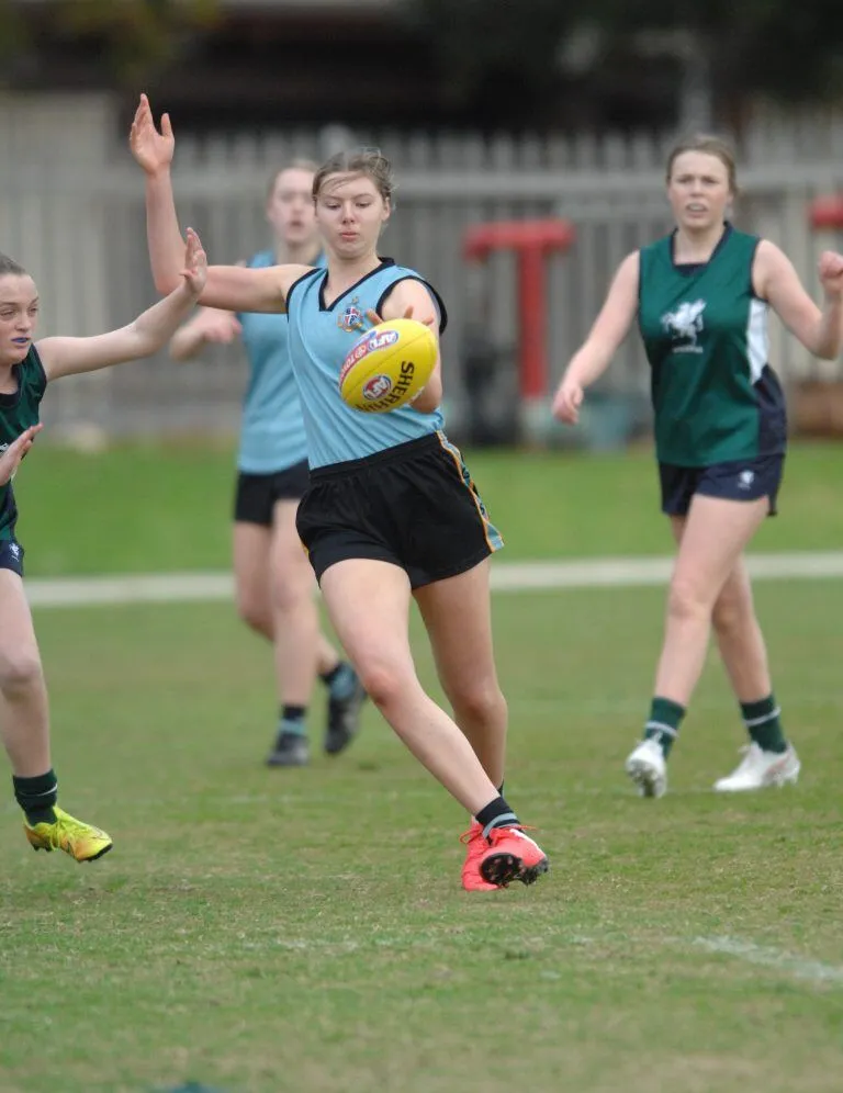 Estudiantes de la Geelong Grammar School juegan al fútbol australiano en un campo de césped.