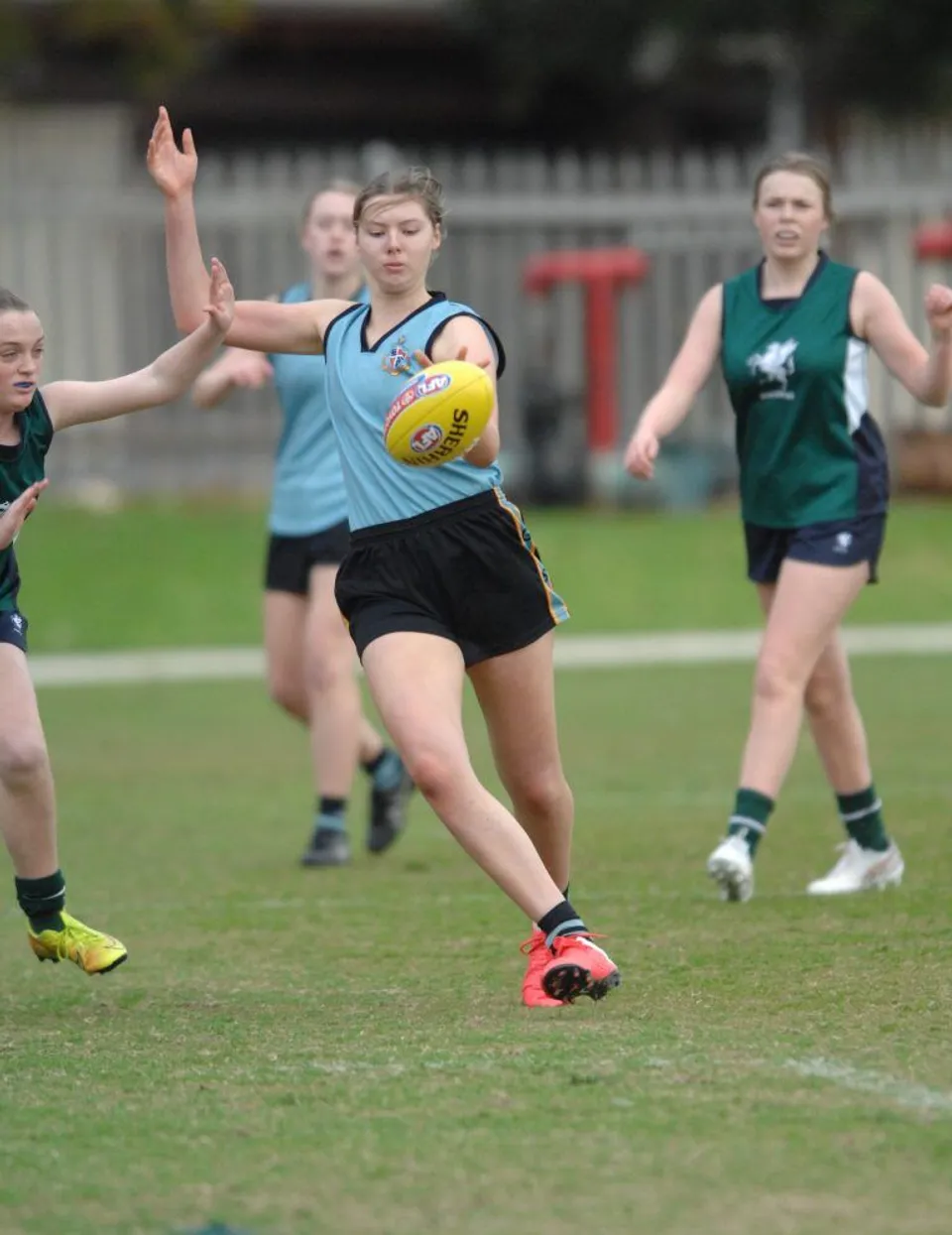 Studenti della Geelong Grammar School giocano ad Australian rules Football su un campo d'erba.