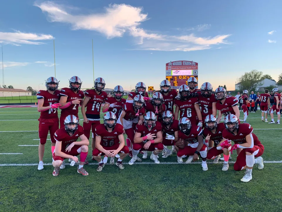 Un gruppo di giocatori di football in maglia rossa si trova sul campo sportivo della Danville Community High School.