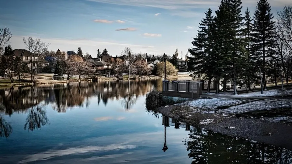 Un tranquillo lago invernale riflette gli edifici e gli alberi nel terreno del Collège Pierre-Elliott-Trudeau.