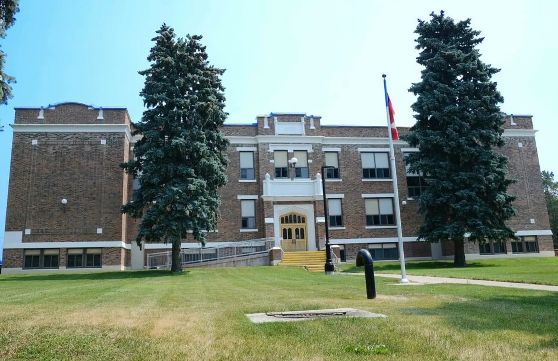 L'edificio in mattoni della Lethbridge School Division si trova accanto a un prato ben curato e ad alte conifere.