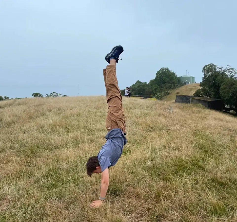 Handstand auf einer hügeligen Wiese in Neuseeland