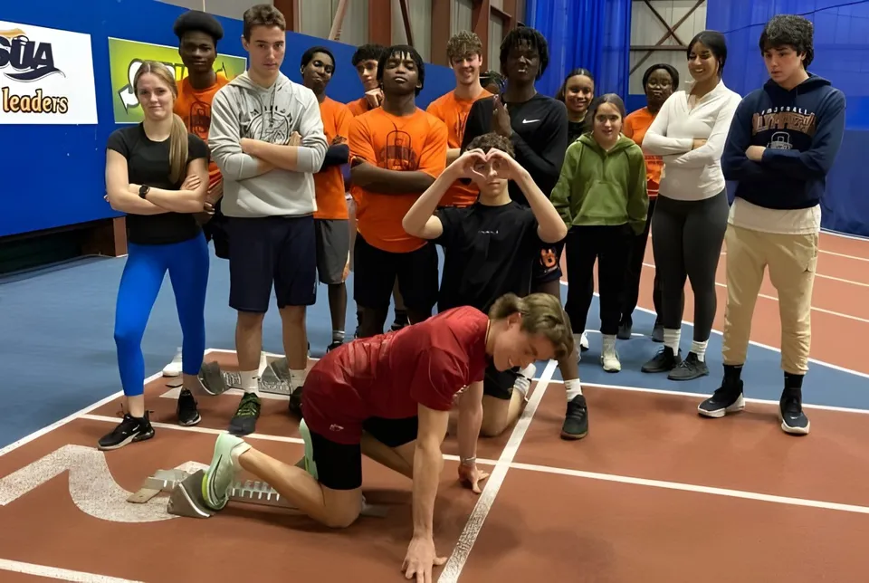Studenti della École L’Odyssée posano su una pista di atletica al coperto.