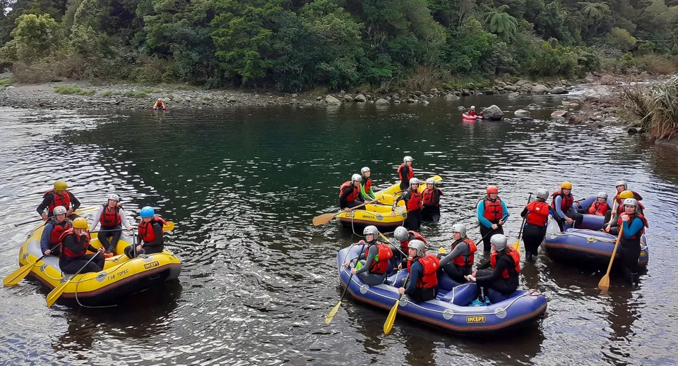 Studentesse del Sacred Heart Girls' College a New Plymouth mentre fanno rafting su un fiume circondato dal verde.