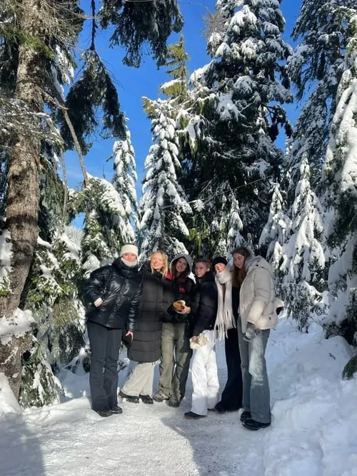 Gruppo di ragazze in abbigliamento invernale in un bosco di abeti innevati