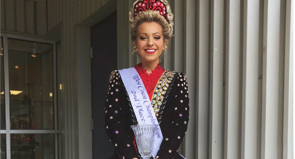 Una donna con una corona elaborata si trova davanti a un edificio con colonne nel campus della Port Moody Secondary School.