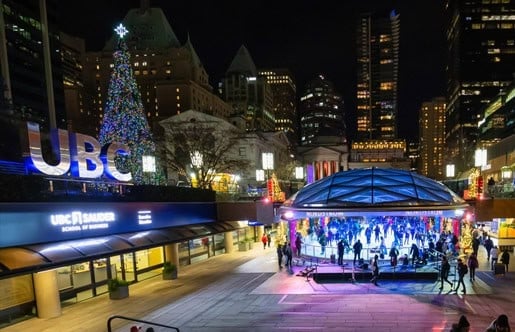 Pista de patinaje sobre hielo iluminada de noche junto a un gran árbol de Navidad