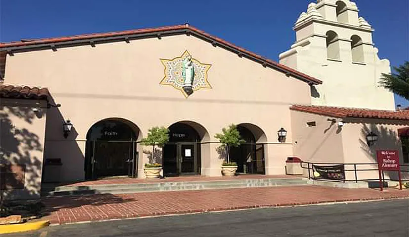 L'edificio in stile spagnolo della Bishop Alemany High School con campanile e arcate ad arco su cielo blu.