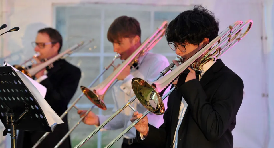 Studenti della Dean Close School suonano vari ottoni su un palco durante un'esibizione.