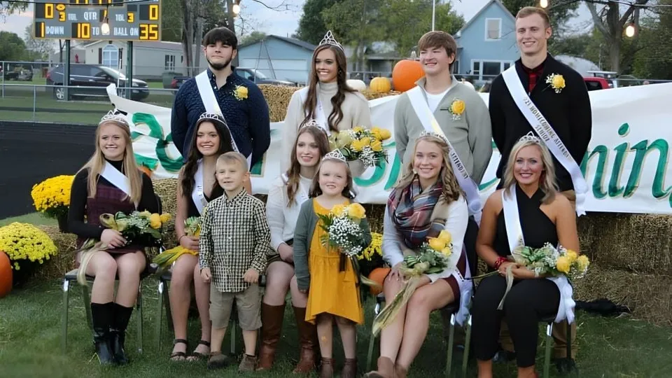 Un grupo de estudiantes de Ridgemont High School está de pie frente a un estadio deportivo con flores en la mano.