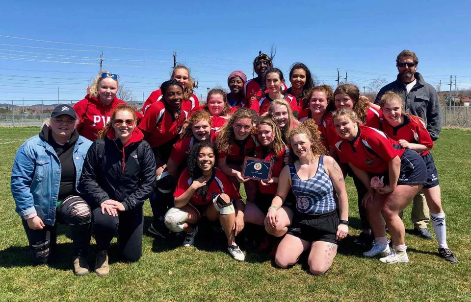 Un gruppo di studentesse in divisa rossa si trova su un prato nel campus della Prince of Wales Collegiate.