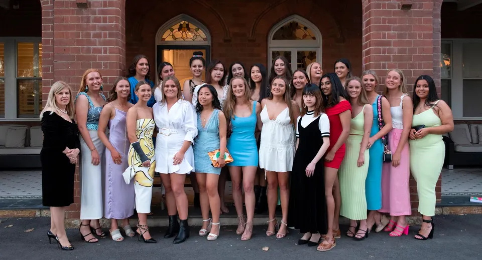Un gruppo di giovani donne in abiti colorati si trova davanti a un edificio in mattoni nel campus del Pymble Ladies College.