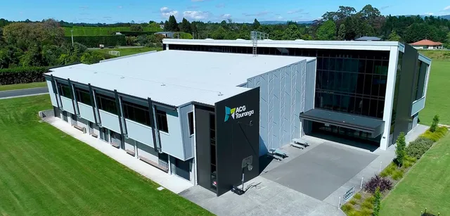 Das moderne mehrstöckige Gebäude der ACG Tauranga steht in einer grünen Landschaft mit großen Fenstern.