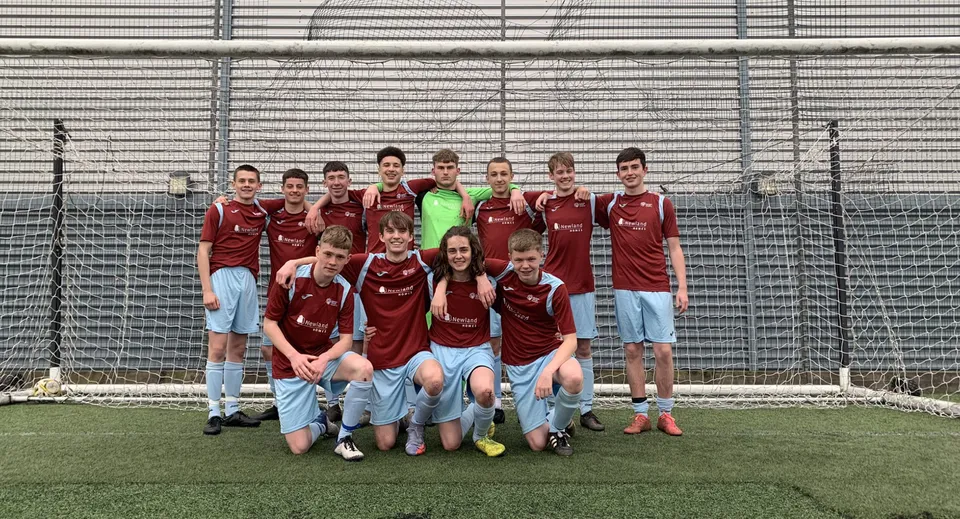 Un gruppo di studenti e studentesse della Hanham Woods Academy posa insieme sul campo da calcio.