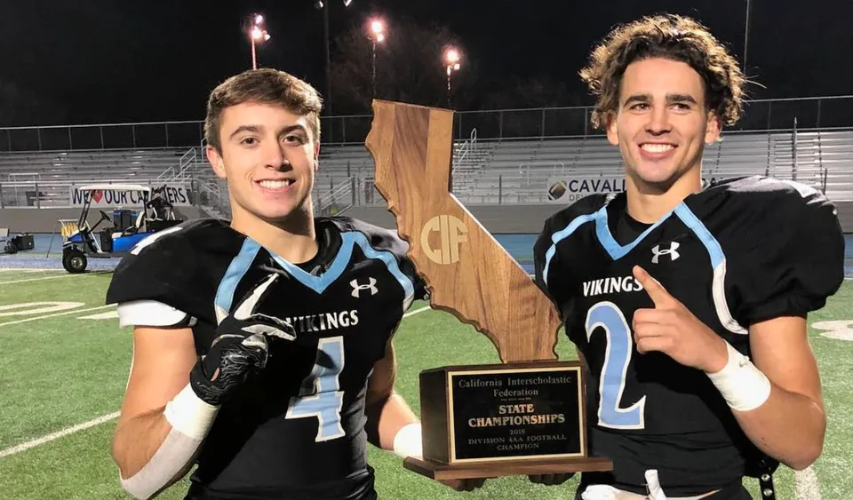 Due studenti della Pleasant Valley High School in divisa sportiva tengono in mano un trofeo sul campo sportivo.