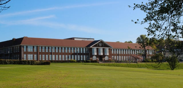 L'edificio in mattoni a più piani con tetto rosso sul prato verde del Varndean College.