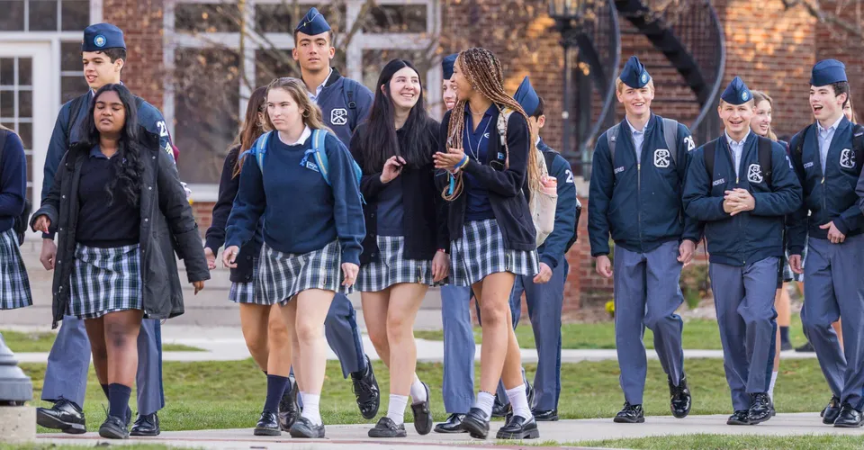 Studenti della Indiana Private Highschool camminano insieme nel campus con edifici in mattoni sullo sfondo.