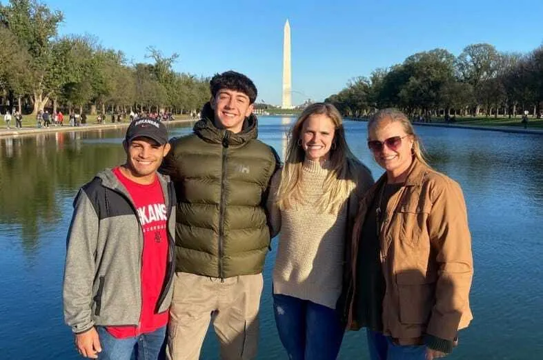 Cuatro personas sonrientes frente al estanque con el Obelisco de Washington de fondo