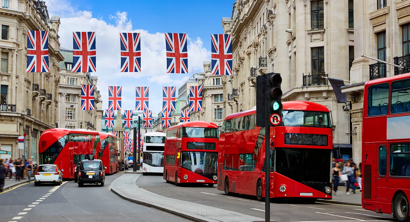 Autobuses rojos de dos pisos en una calle de Londres decorada con banderas del Reino Unido