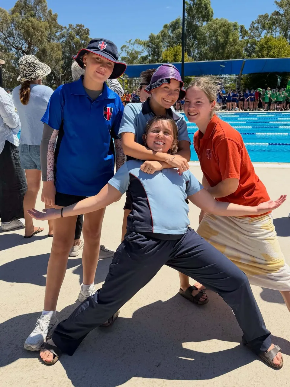 Quattro studentesse del Cathedral College Wangaratta posano sorridenti accanto a una piscina all'aperto.