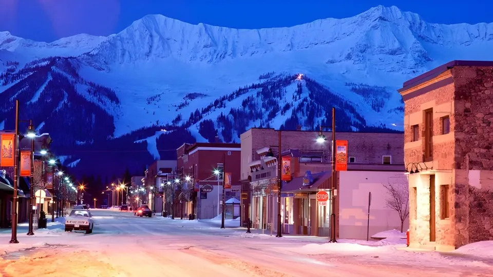 Paesaggio montano innevato con una strada illuminata davanti all'edificio scolastico della École Sophie Morigeau.