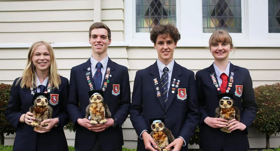Quattro studenti della St. Peter's School Cambridge sono davanti a un edificio in legno e tengono ciascuno un piccolo cane.