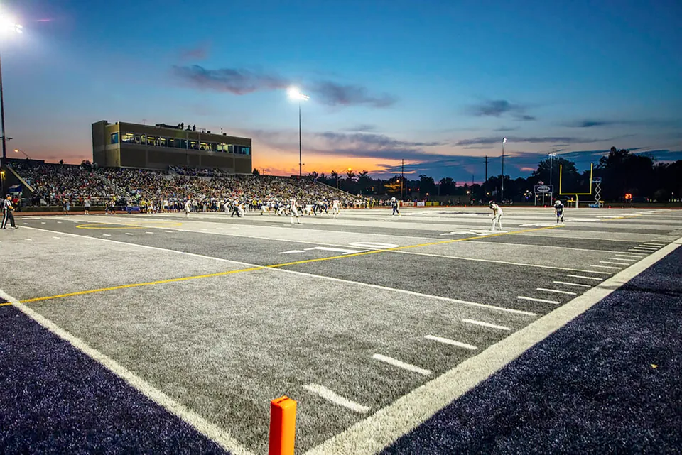 Il campo da football della Morgan High School è visibile al tramonto con gli spettatori nello stadio.