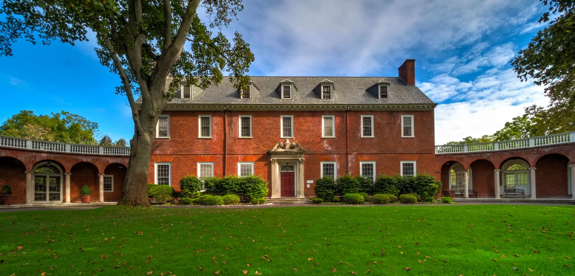 La villa patronale della The Knox School sorge circondata da un prato curato e alti alberi sotto un cielo blu.