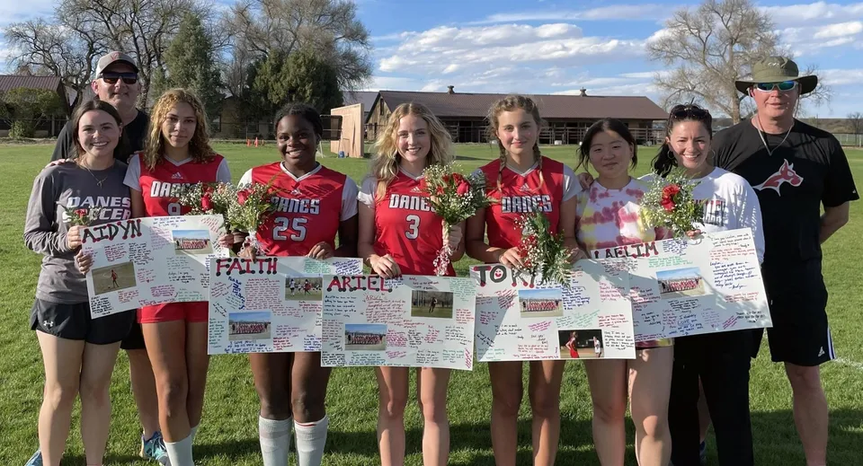 Un gruppo di giovani atlete si trova sul campo sportivo della Fountain Valley School of Colorado con cartelli di supporto.