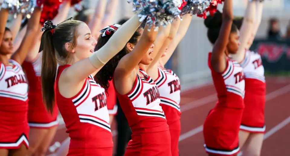 Un gruppo di cheerleader del Paradise Valley Unified School District si esibisce sul campo sportivo davanti agli spettatori nello stadio.