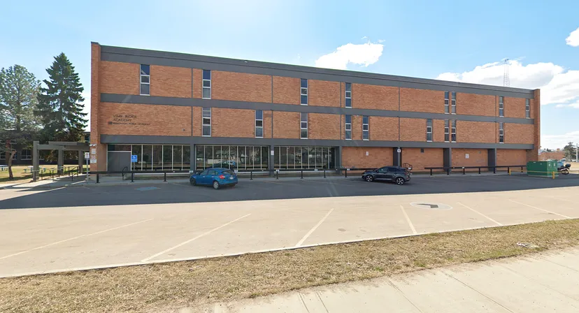 L'edificio in mattoni a più piani dal design moderno della Vimy Ridge Academy si trova di fronte a un parcheggio pavimentato e ad aree verdi.