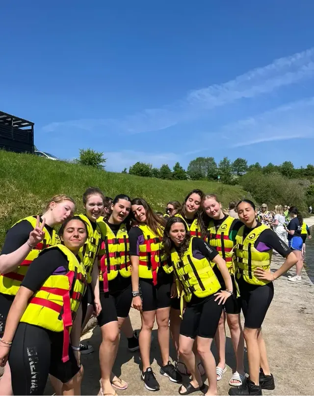 Gruppo di ragazze in giubbotti di salvataggio gialli su una spiaggia prima di un'attività acquatica