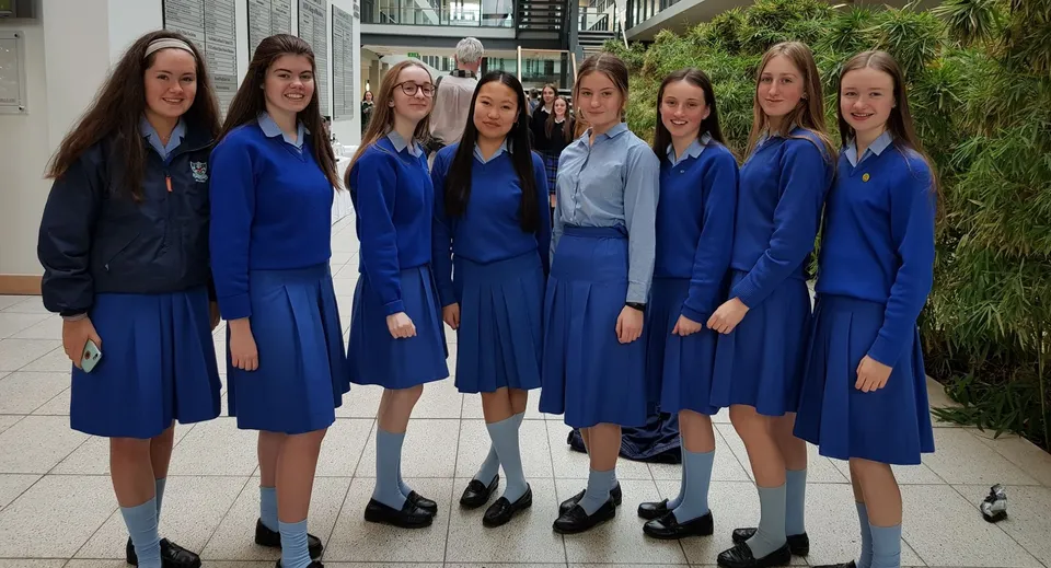 Un gruppo di studentesse in divisa blu si trova insieme in uno spazio interno nel campus della St. Joseph of Cluny.