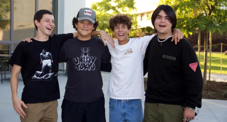Quattro studenti della Ojai Valley School sono insieme all'aperto e sorridono davanti a un edificio circondato da alberi.