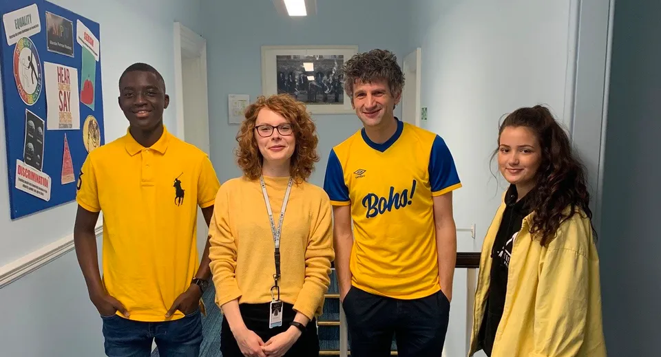 Quattro studenti e studentesse sono insieme in un'aula della MPW Birmingham davanti a dei cartelloni informativi.