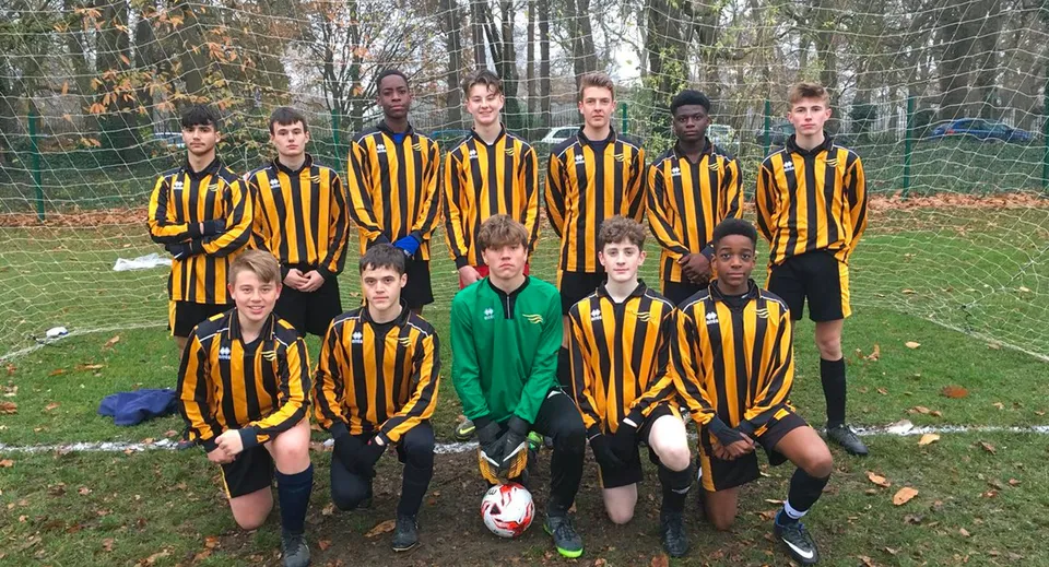 Un gruppo di giovani calciatori si trova sul campo sportivo della Larkmead School con maglie gialle e nere.