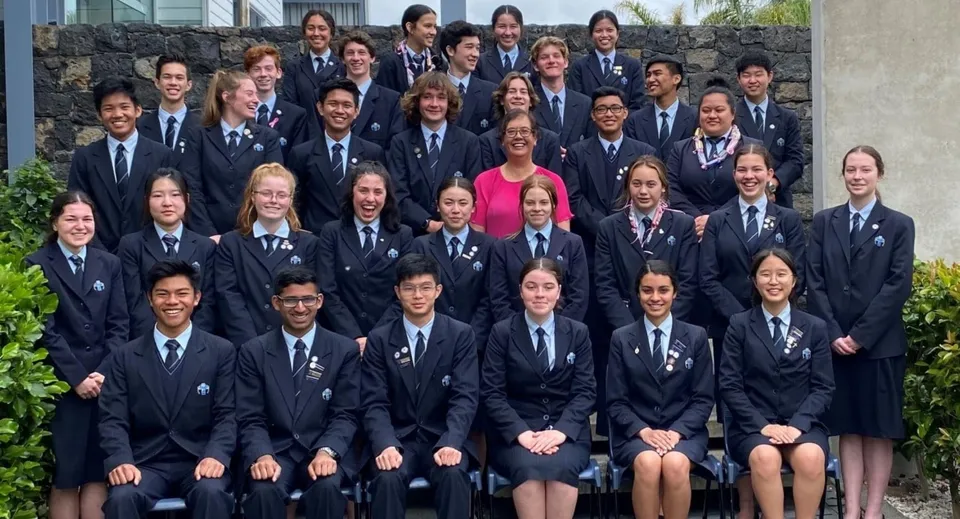 Un grande gruppo di studenti in uniforme scolastica si riunisce all'aperto nel campus del Sancta Maria College.