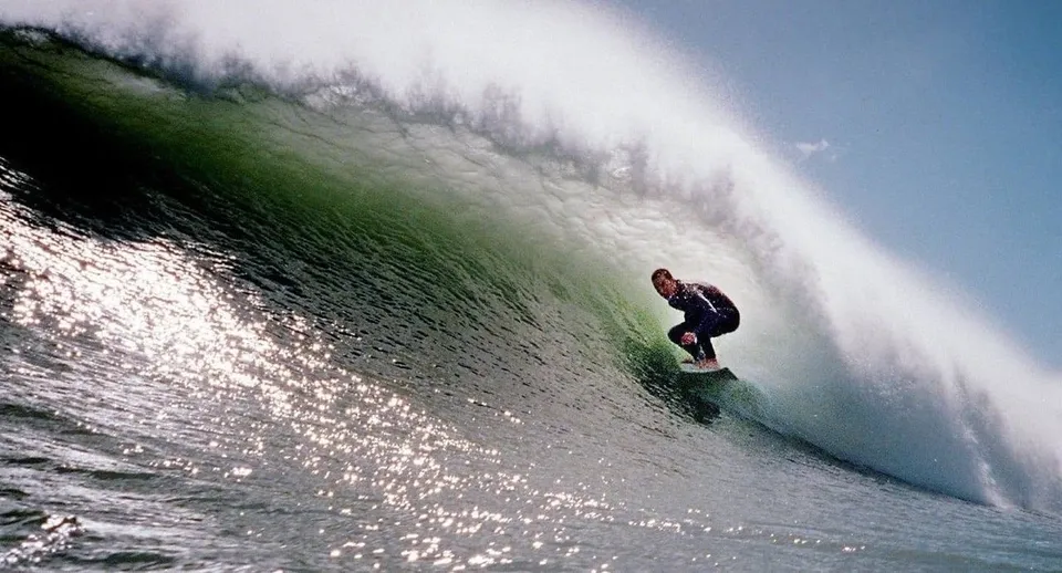 Un surfista cavalca un'onda enorme sulla costa vicino alla New Plymouth Boys' High School.
