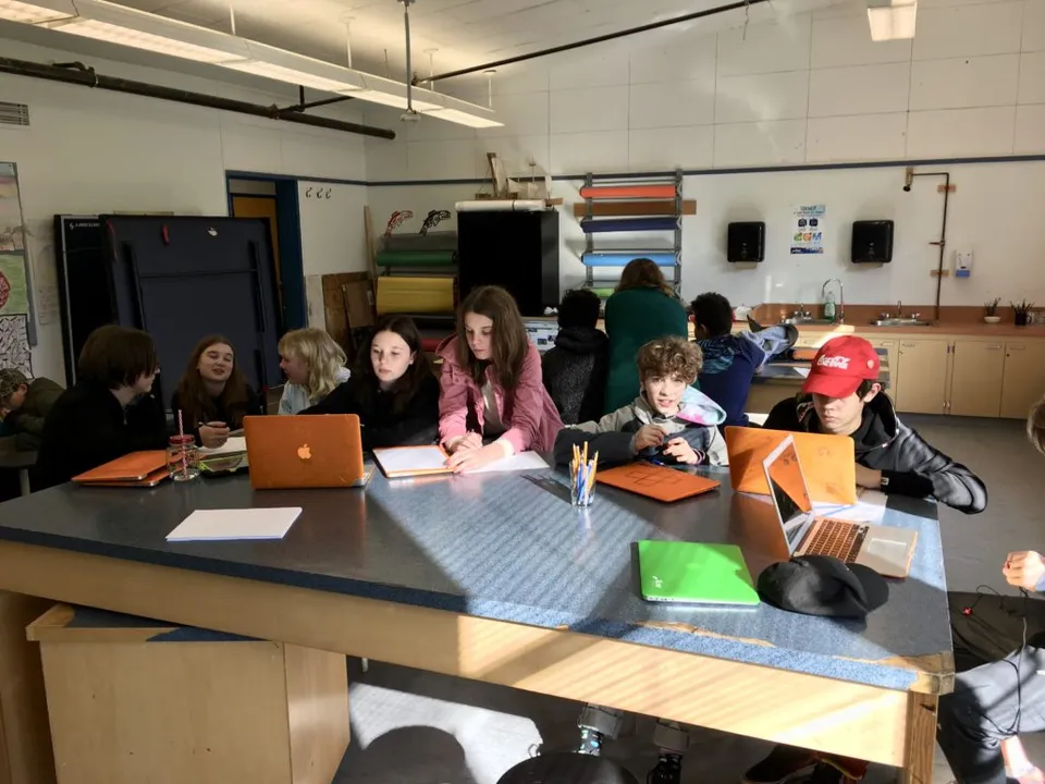 Studenti e studentesse della École Côte du Soleil lavorano insieme a un tavolo in un'aula.